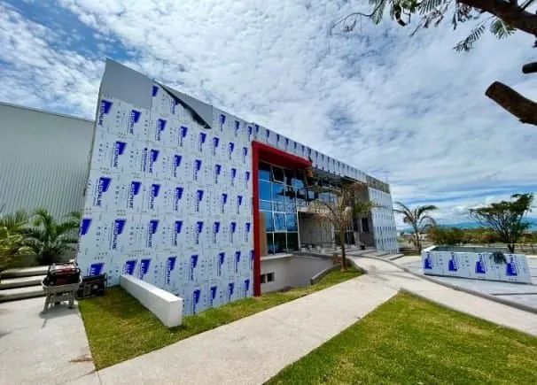 Edificio con fachada perforada en panel Alcopalme con acento rojo