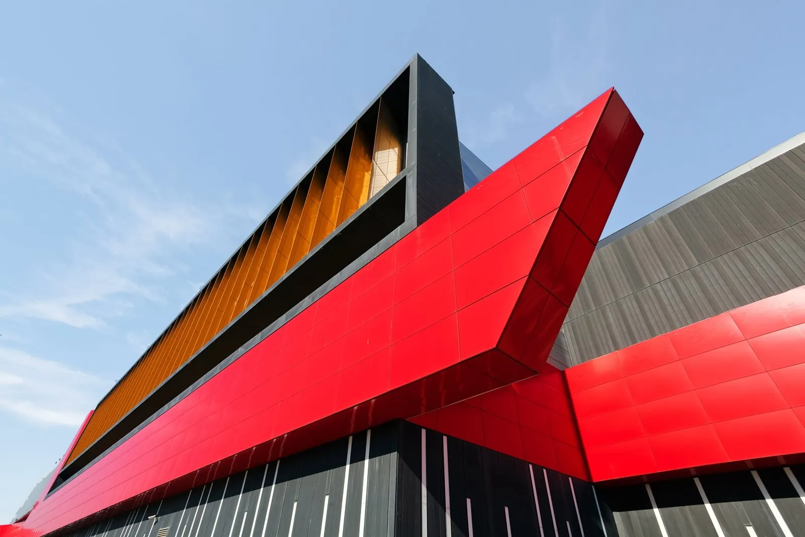 Fachada corporativa con volúmenes en panel de aluminio compuesto rojo y plata